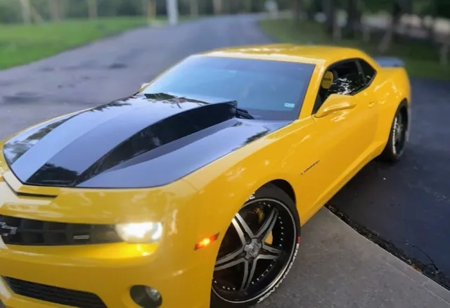 A yellow car with black stripes, seen from the side.