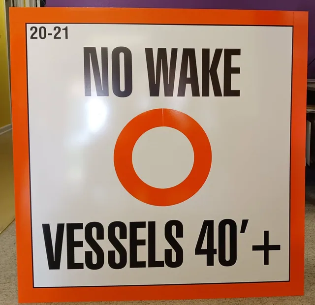A no wake sign with an orange ring and black lettering.