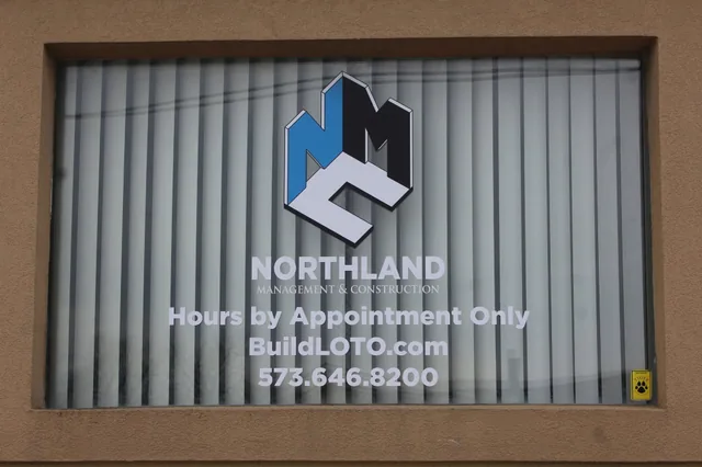 White window lettering with a logo, hours and a phone number.