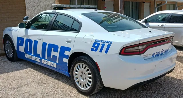Blue police lettering on a white patrol car, seen from the rear.
