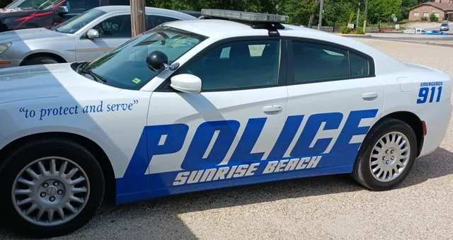 Blue police lettering along the side of a white patrol car.