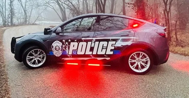 A police car with lettering and red lighting at night.
