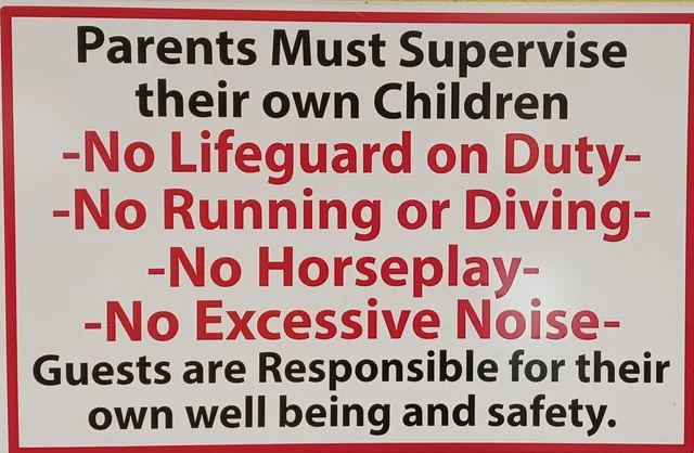 A pool rules sign with red and black lettering.