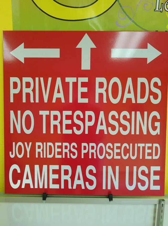 A red private roads sign with white lettering and arrows.