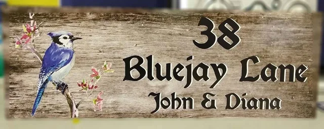 A family address sign with a blue bird and wood-pattern background.