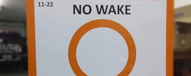 A white no-wake sign with an orange circle.