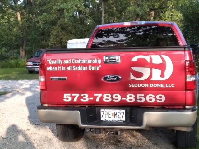 White lettering and a logo on the tailgate of a red pickup.