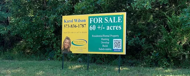 A green and yellow property sign on posts.