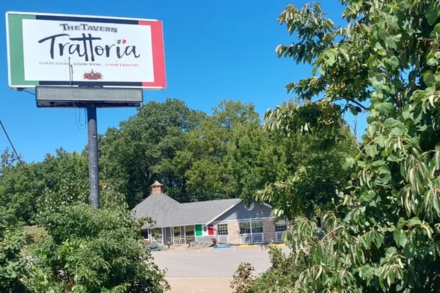 A freestanding business sign beside trees.