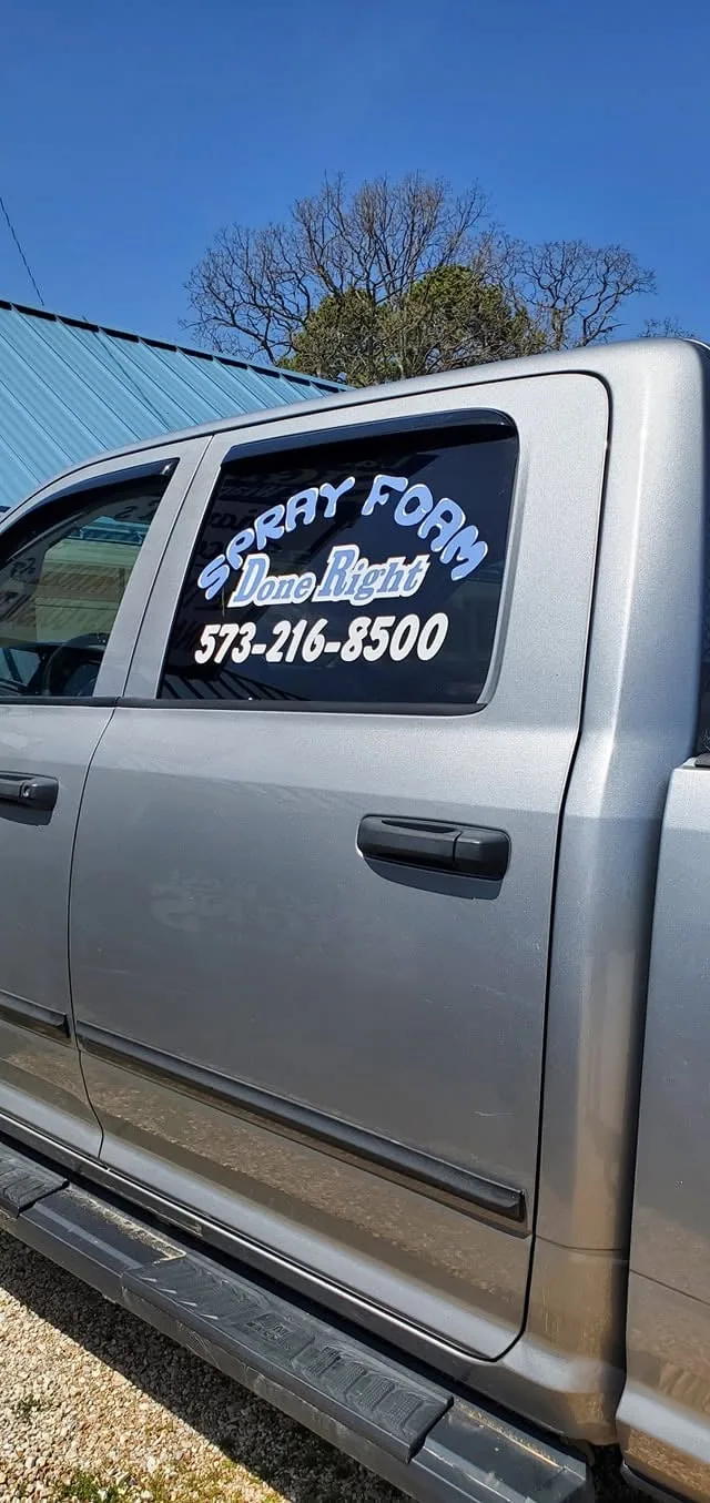 Door lettering with a logo and phone number on a gray pickup.